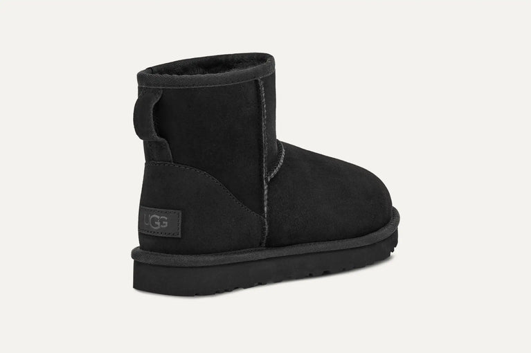 Black UGG boot on a light gray background. UGG Women's Classic Cozy Sheepskin Mini II Boot in volonka