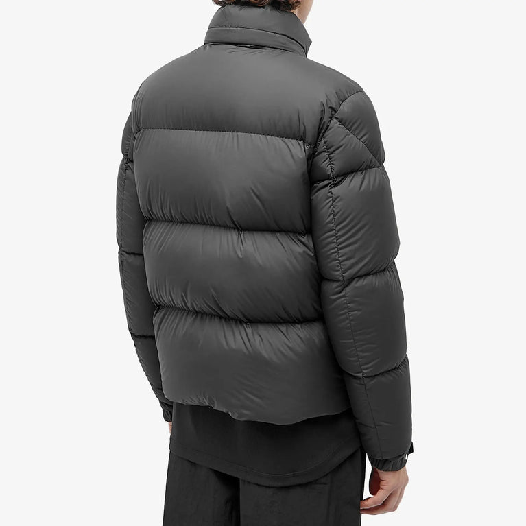 Person wearing a dark gray puffer jacket on a white background