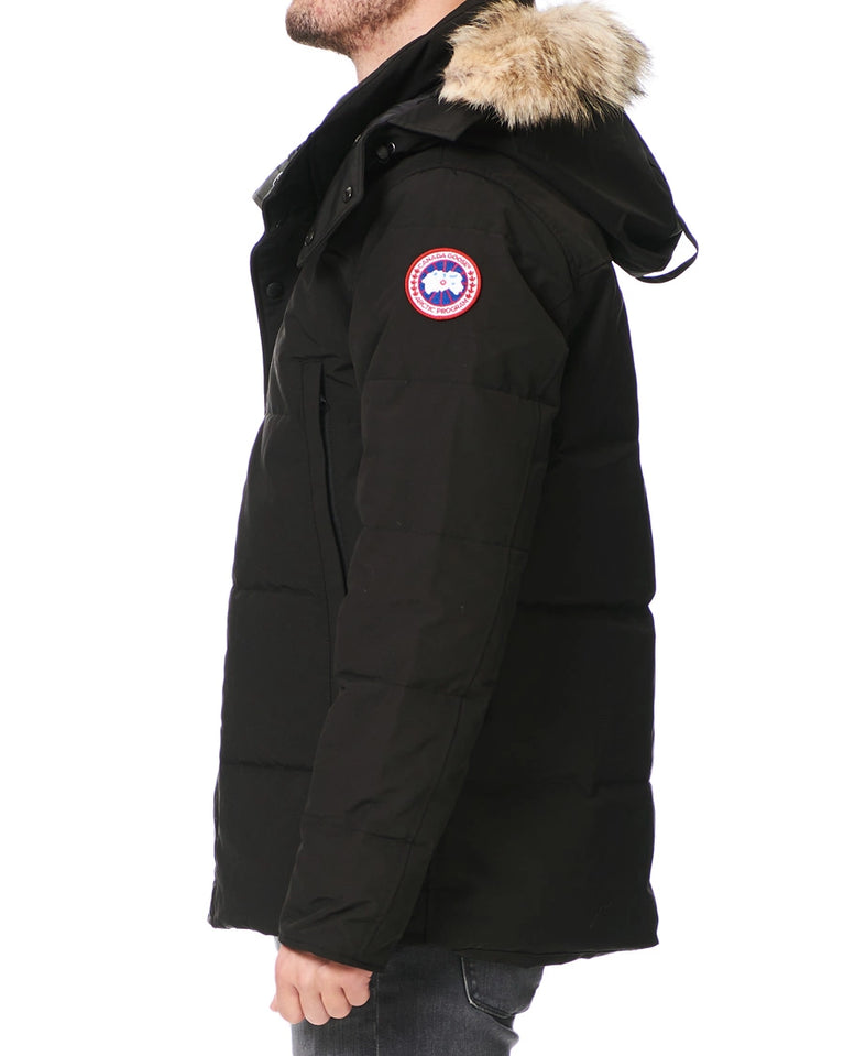 Black parka jacket with fur hood and Canada Goose logo on a white background. Unisex Canada Goose Wyndham Parka with Fur jacket