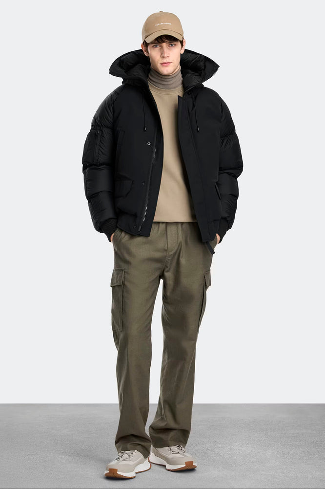 Man wearing a black jacket, beige cap, beige sweater, Canada Goose Paradigm Chilliwack Bomber Unisex Down Jacket at Volonka store.