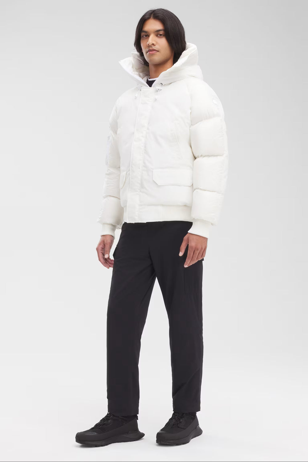 Man wearing a white puffer jacket and black pants, Canada Goose Paradigm Chilliwack Bomber Unisex Down Jacket at Volonka store.