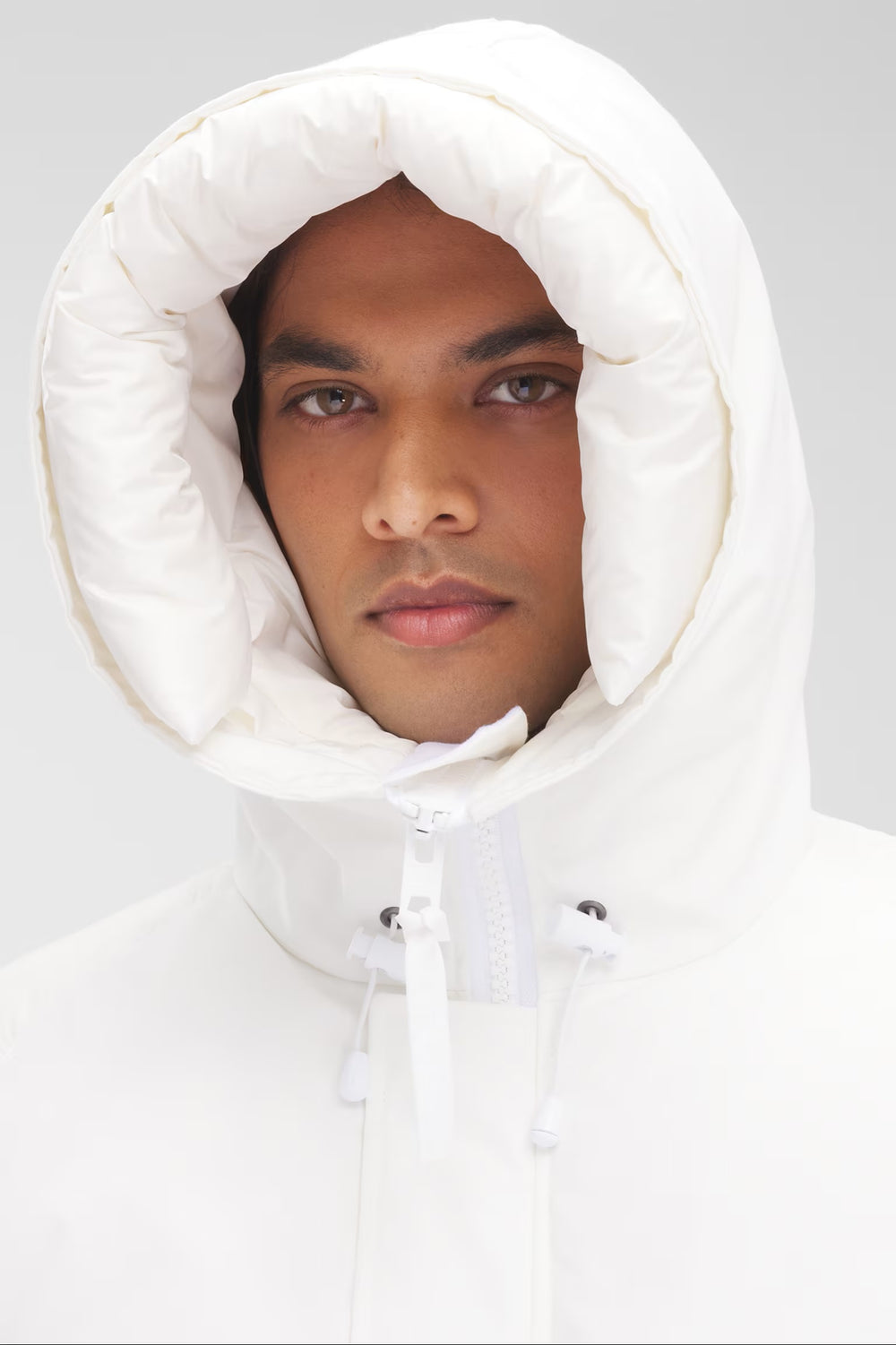 Man wearing a white hooded jacket, Canada Goose Paradigm Chilliwack Bomber Unisex Down Jacket at Volonka store.