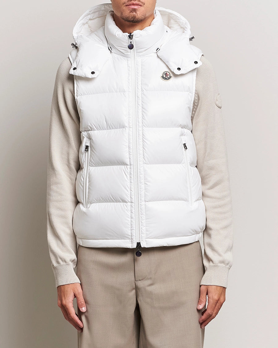 man wearing a white puffer vest over a beige sweater. Moncler unisex Bormes down vest jacket