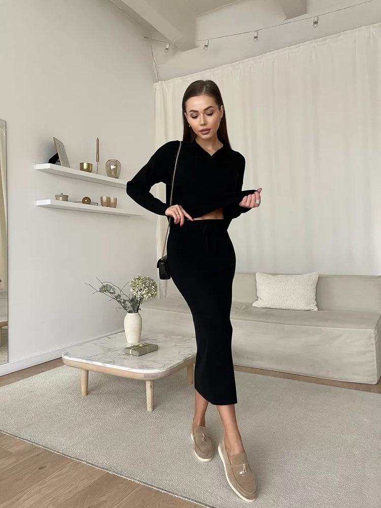Woman in a black outfit standing in a modern living room.