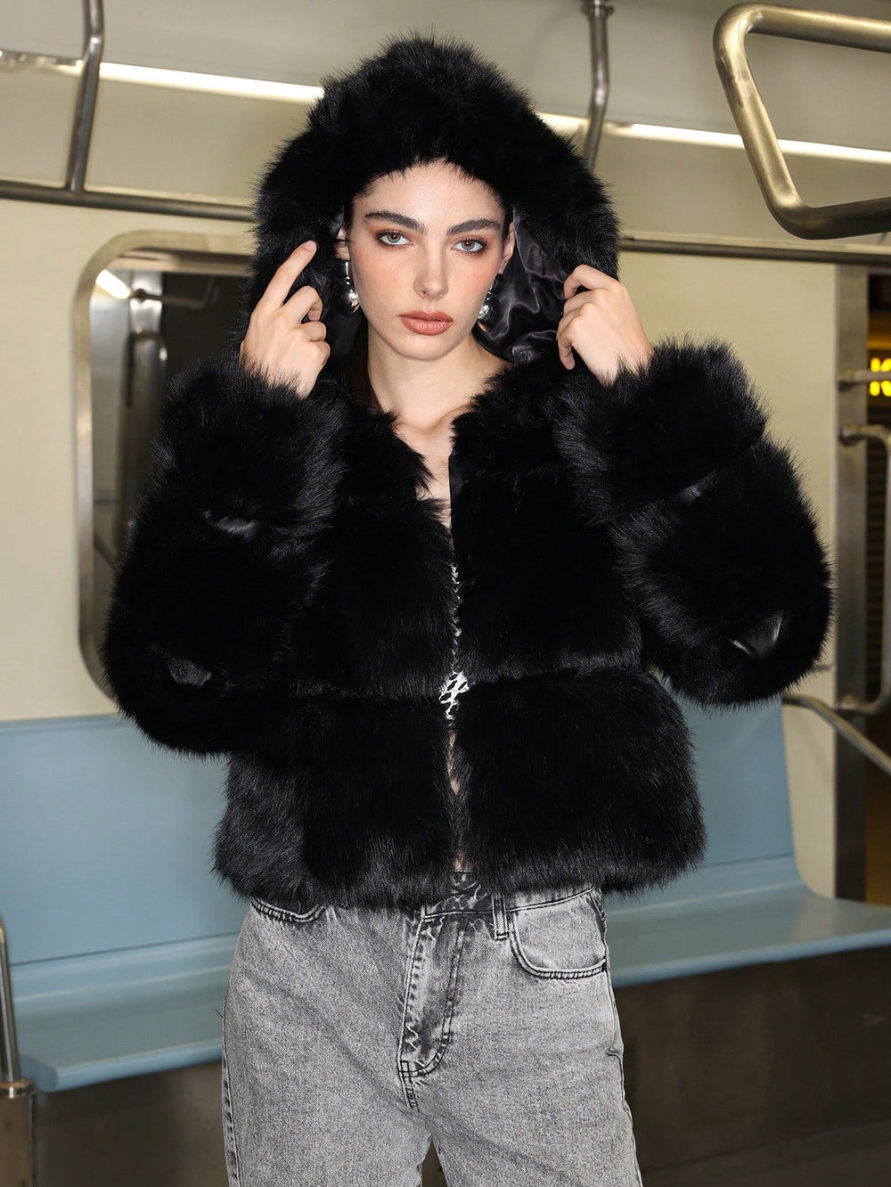 Person wearing a black fur coat on a subway train
