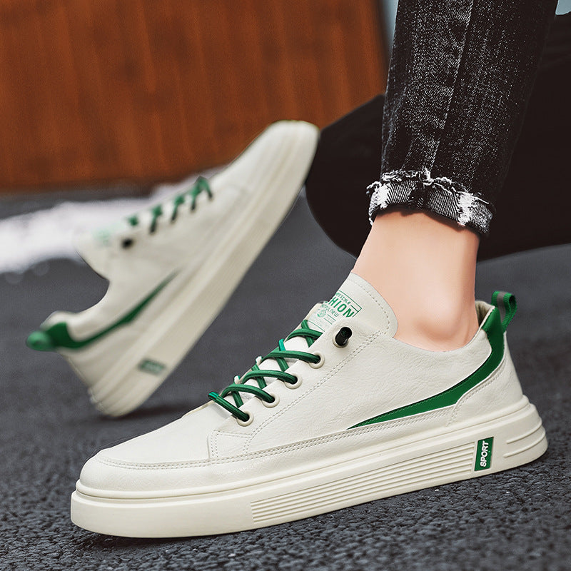 White sneakers with green accents worn by a person on a dark surface.