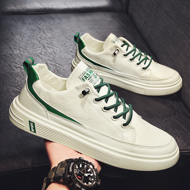 White sneakers with green accents held by a person wearing a black watch.