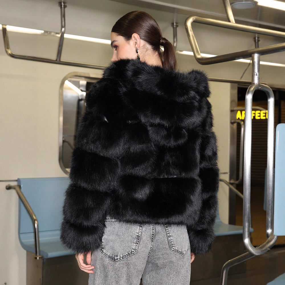 woman wearing a black fur coat on a subway train