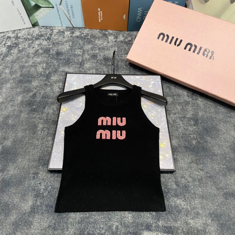 Black tank top with pink 'MIU MIU' logo on a hanger, with Miu Miu packaging in the background.