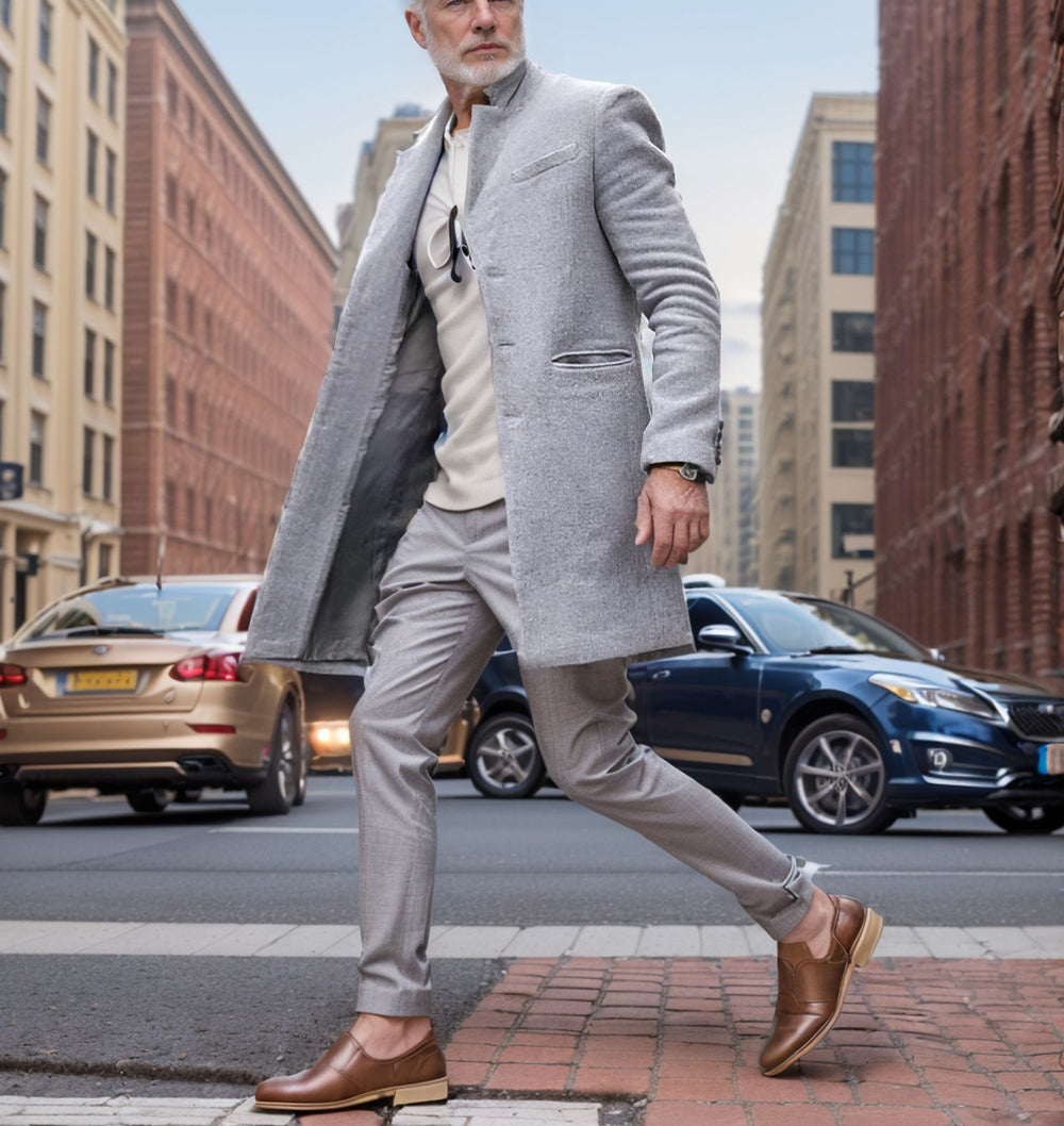 Man in a gray coat and pants walking on a city street.