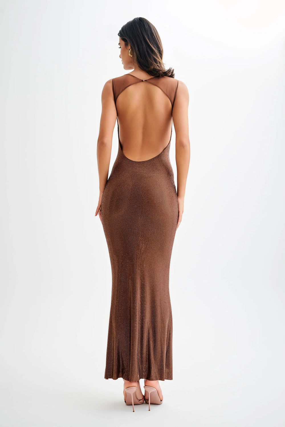 Back view of a woman in a brown backless maxi dress, showcasing a slim-fit design and elegant style.