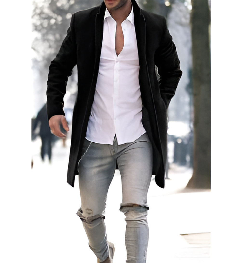 Person wearing a black overcoat, white shirt, and light gray jeans in a snowy outdoor setting.