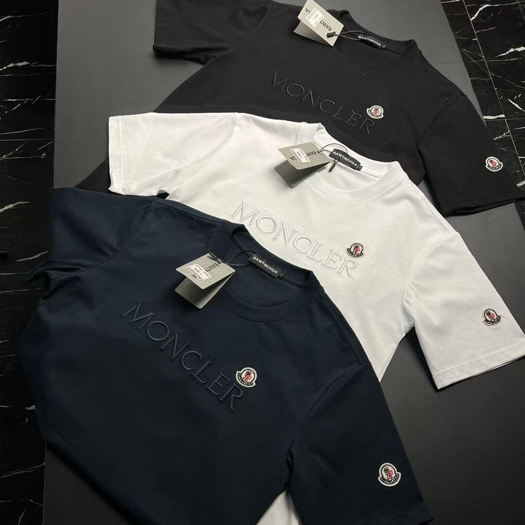 Moncler t-shirts in black, white, and navy on a dark surface