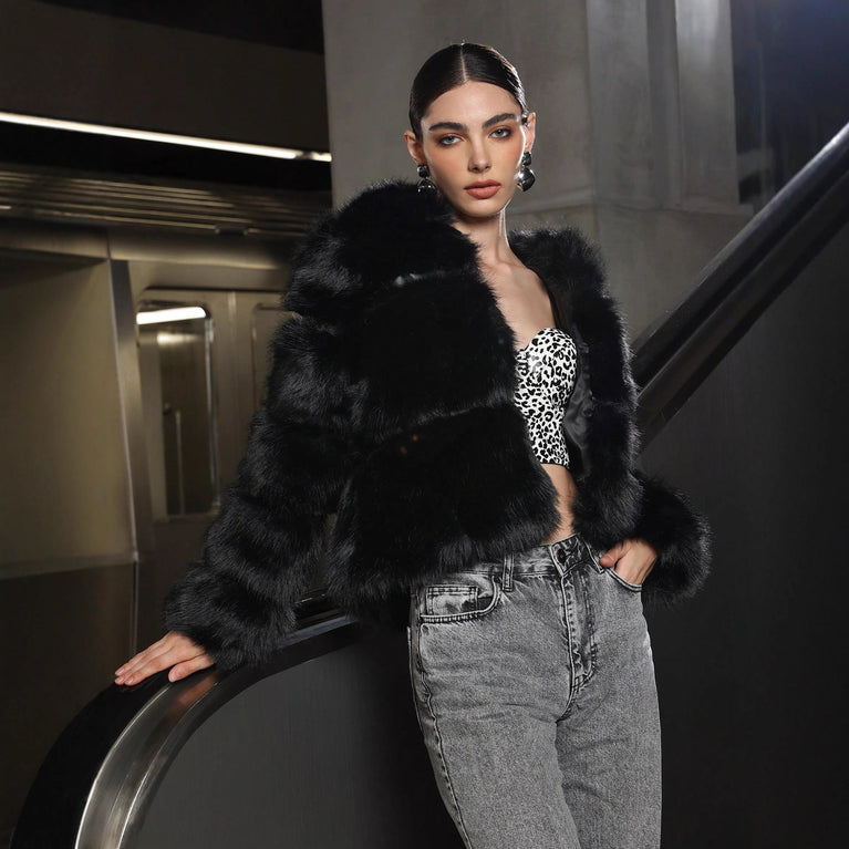 Woman wearing a black fur coat and patterned top in an indoor setting