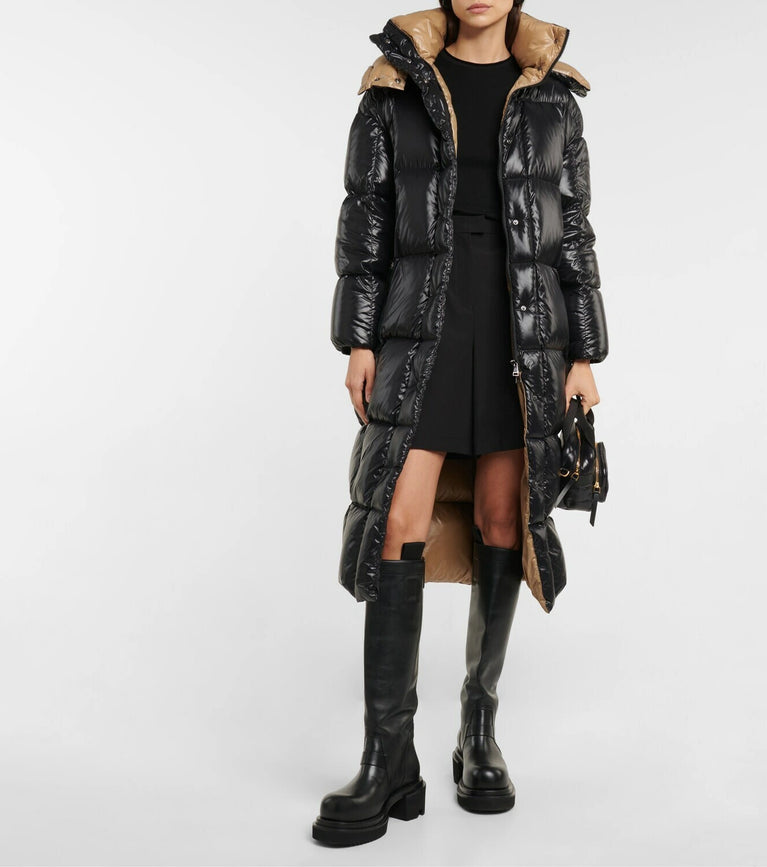 Person wearing a black puffer coat with beige interior and black knee-high boots on a white background