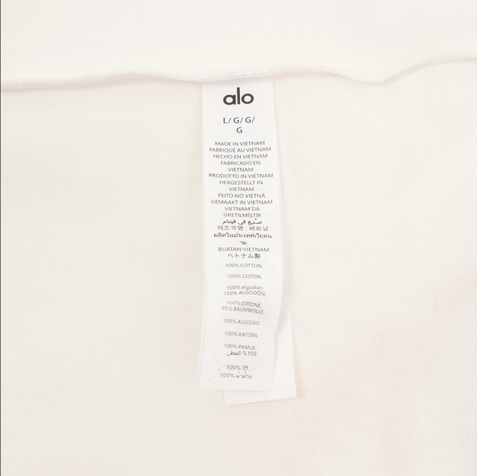 ALO Classic Minimal Short Sleeve Tshirt in white with logo on chest and red tag detail.