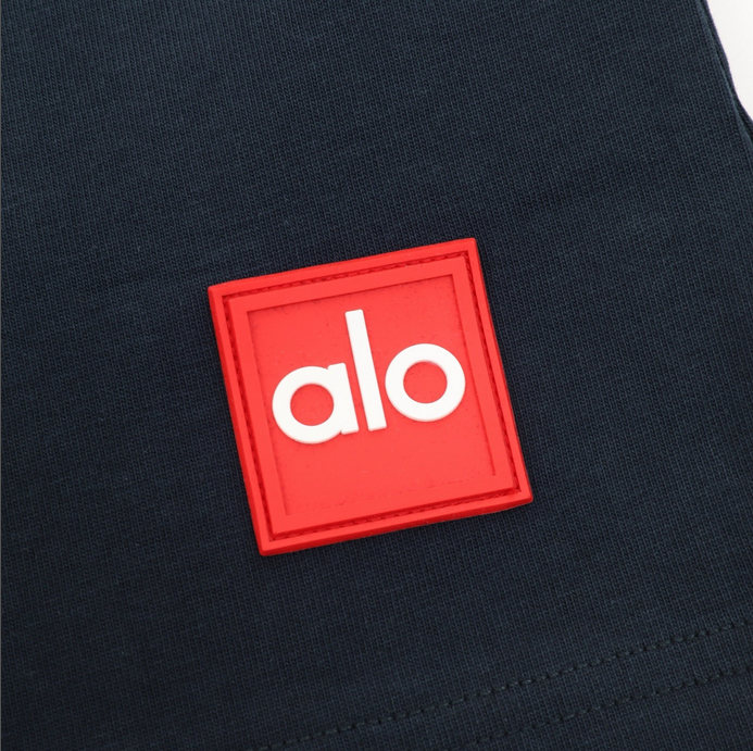 ALO Classic Minimal Short Sleeve Tshirt in navy blue with logo on chest and red tag detail.