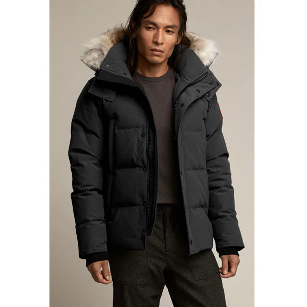 Man wearing Canada Goose Wyndham Parka Goose Men's Winter Jacket at Volonka. Black puffer jacket with fur-lined hood.
