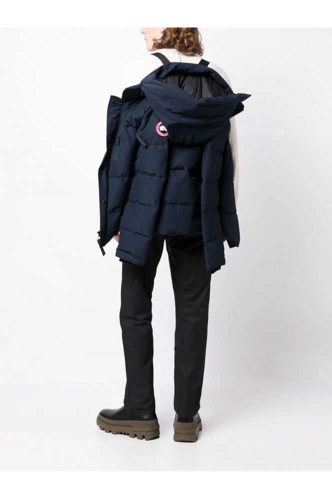 Person wearing a navy blue puffer jacket with a brand logo on a white background. Women's/ men Canada Goose Wyndham Parka with Fur jacket