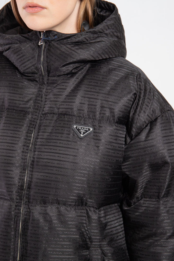 Close-up of a black hooded jacket with a brand logo on a white background