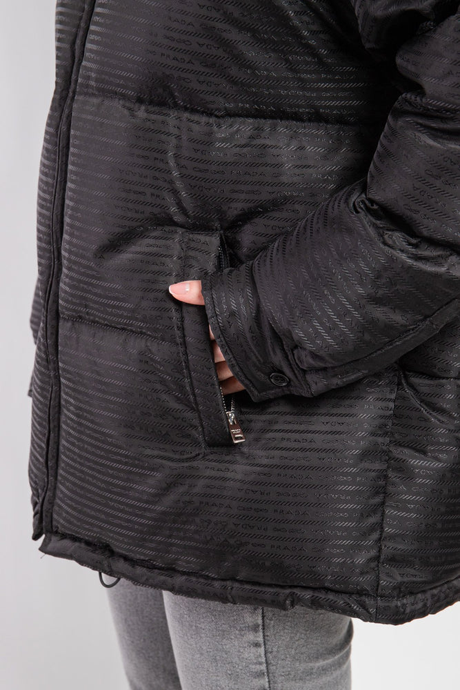 Close-up of a person wearing a black textured jacket with a plain background