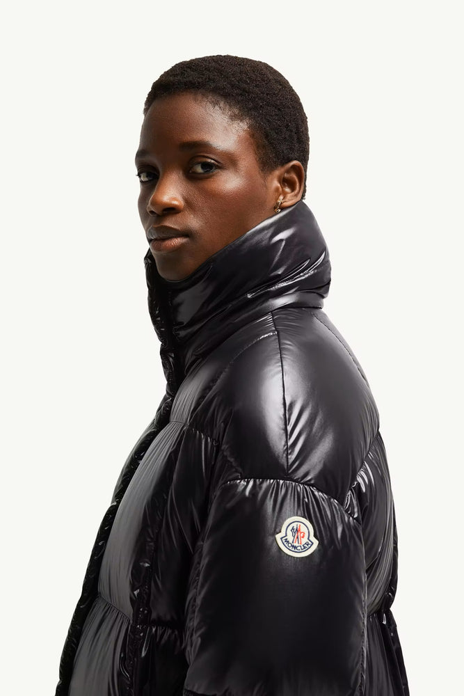 Person wearing a black puffer jacket with a brand logo on a white background