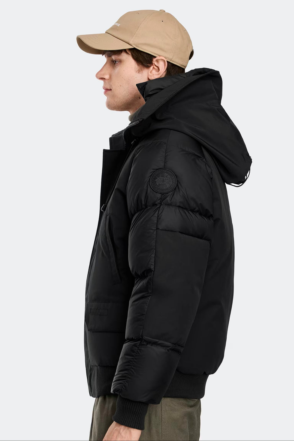 Man wearing a black puffer jacket and beige cap, Canada Goose Paradigm Chilliwack Bomber Unisex Down Jacket at Volonka store.