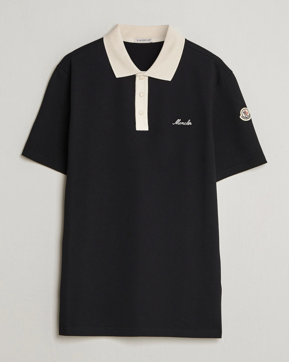Moncler Men Signature Logo Polo displayed on a neutral background, featuring a classic collar and signature logo.