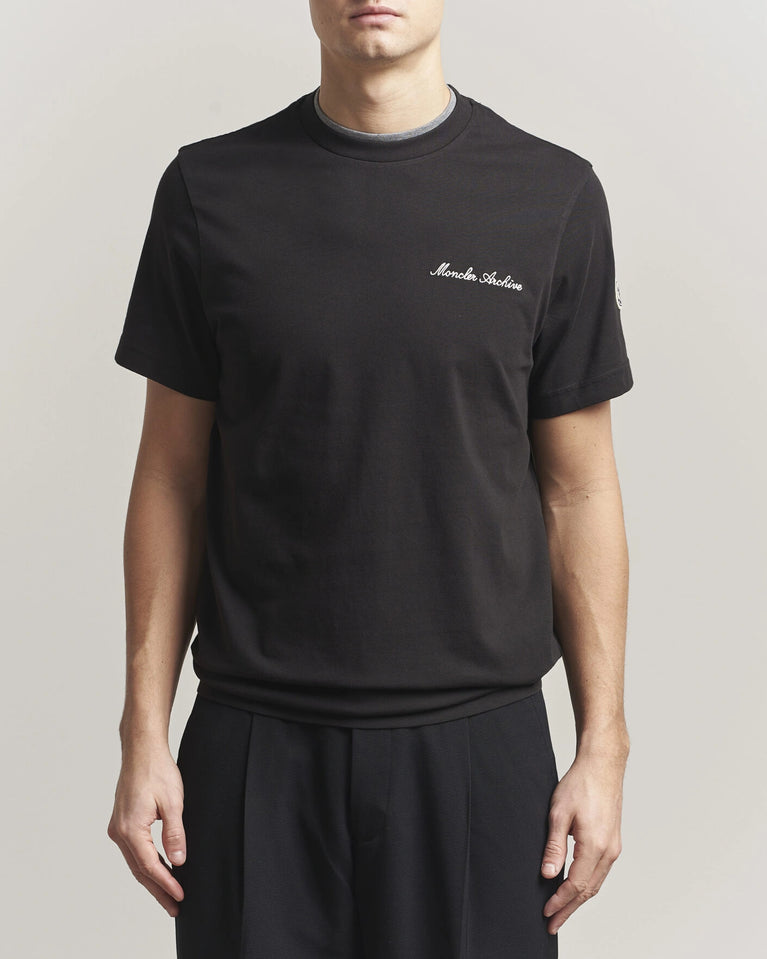Moncler Men Signature Logo Tshirt displayed in black, featuring logo detail and contrasting neckline.