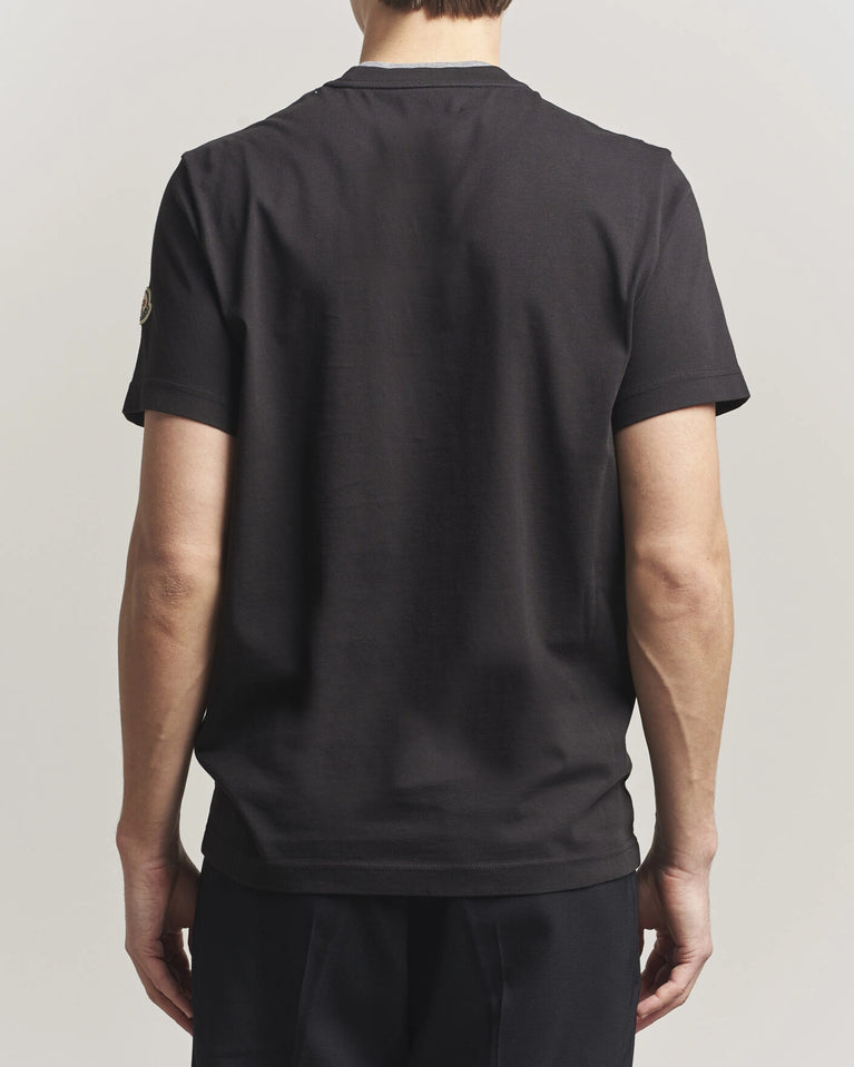 Moncler Men Signature Logo Tshirt displayed in black, featuring logo detail and contrasting neckline.