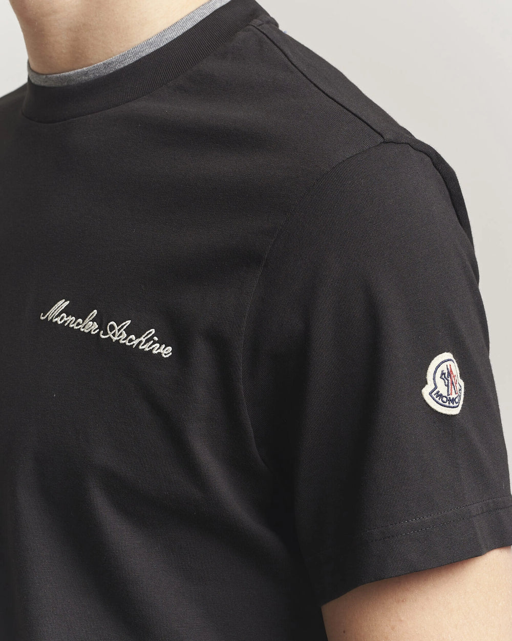 Moncler Men Signature Logo Tshirt displayed in black, featuring logo detail and contrasting neckline.