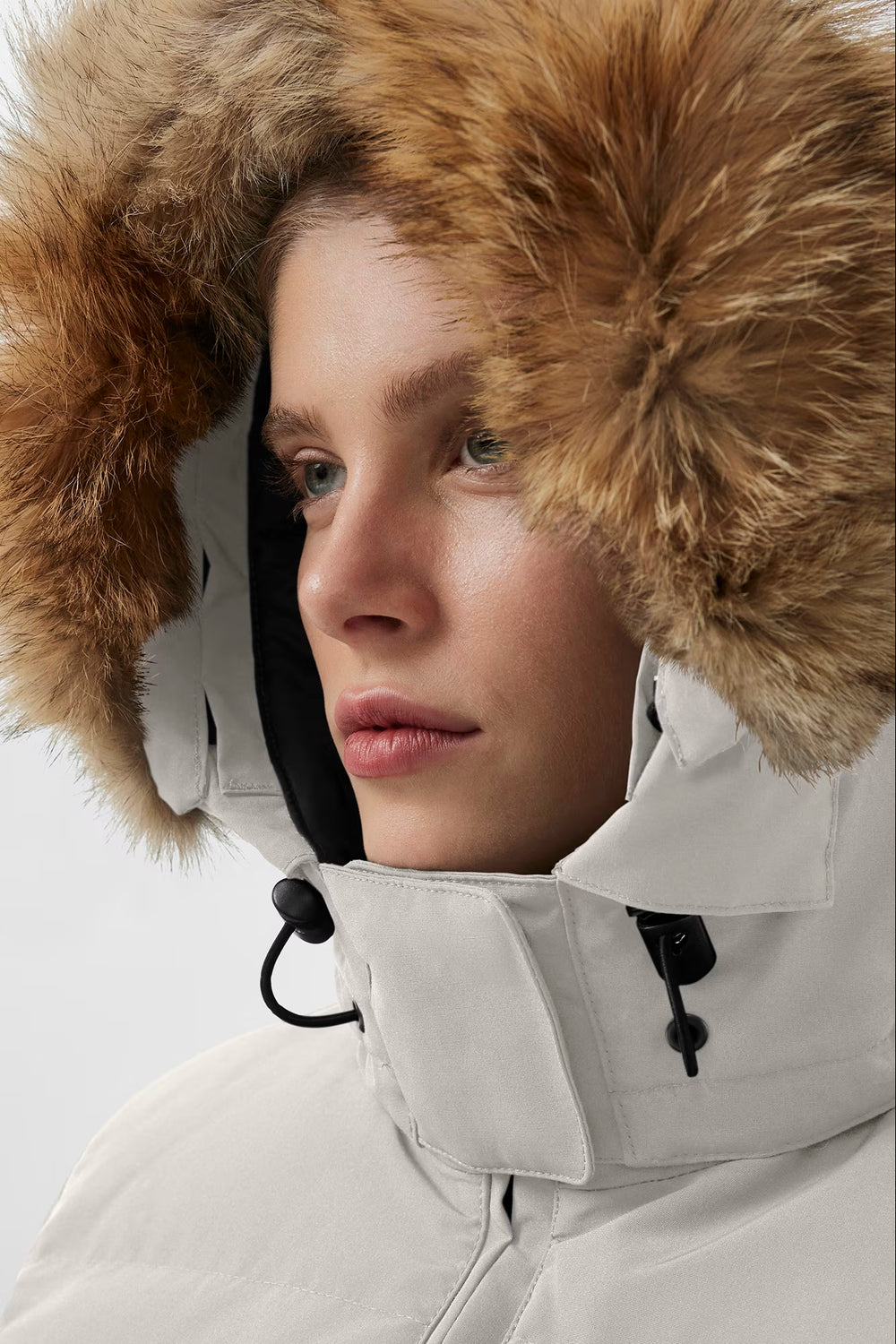 Woman wearing a white winter coat with a fur-lined hood. Canada Goose Chelsea Parka Women's Down Winter Jacket at Volonka store.