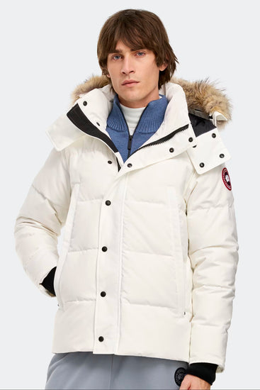 Man wearing a white winter jacket with a fur-lined hood. Canada Goose Wyndham Parka Goose Men's Winter Jacket at Volonka. 