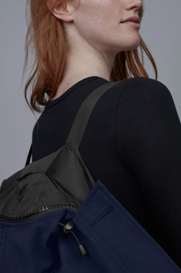 Person wearing a black backpack with a gray background