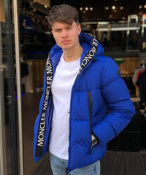 man wearing a blue Moncler jacket with a white shirt and jeans in an indoor setting. Moncler Montcla Short Down Jacket