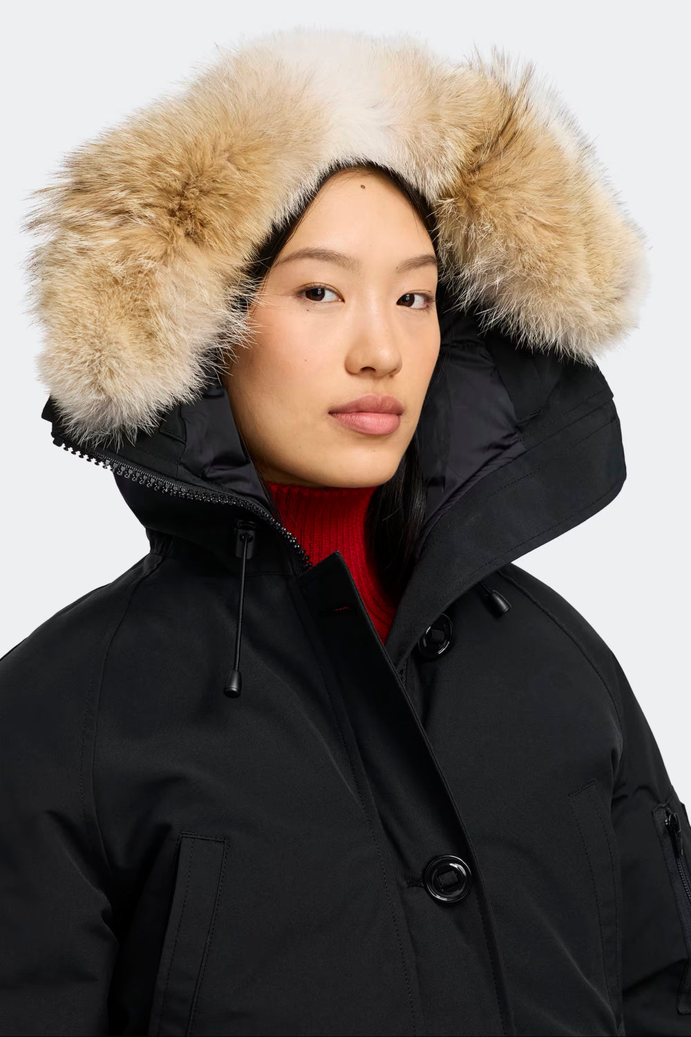 Person wearing a black parka with a fur-lined hood on a white background in volonka store