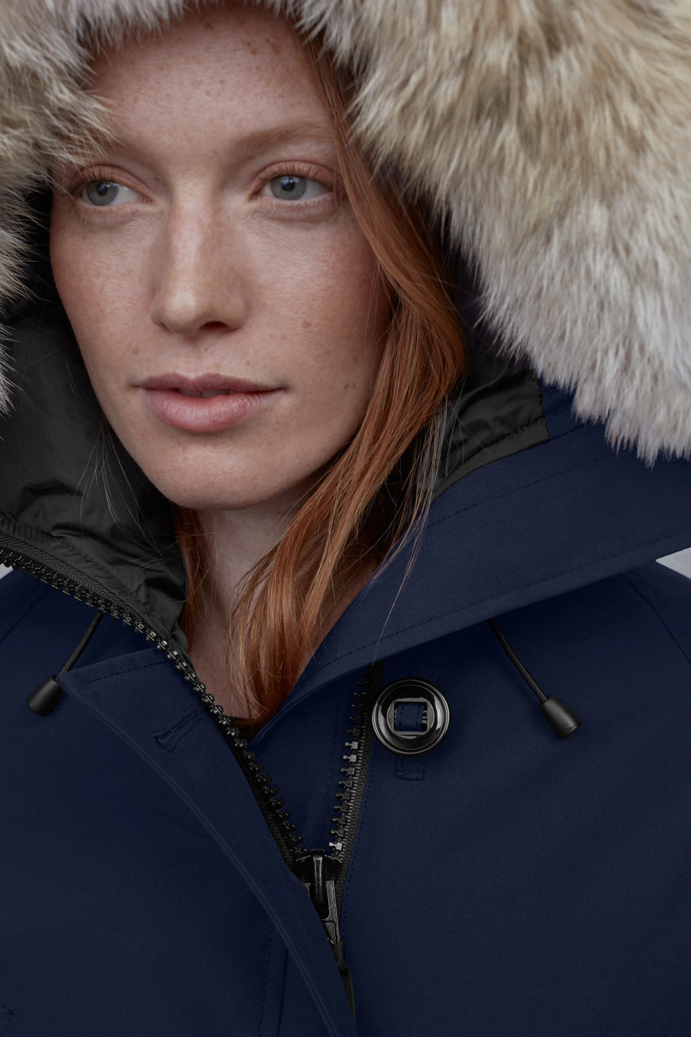 Person wearing a dark blue coat with a fur-lined hood. Canada Goose Chilliwack Bomber Women's Winter Hooded Jacket