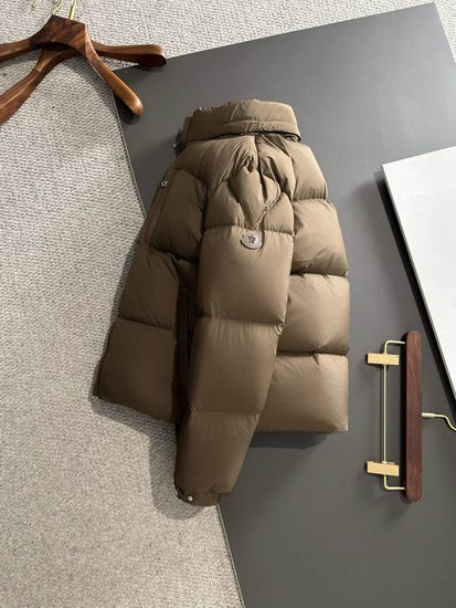 Brown puffer jacket on a dark surface with hangers in the background