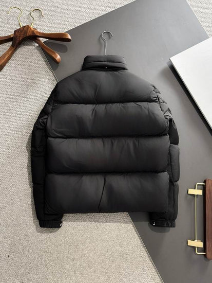 Black puffer jacket on a hanger against a gray background