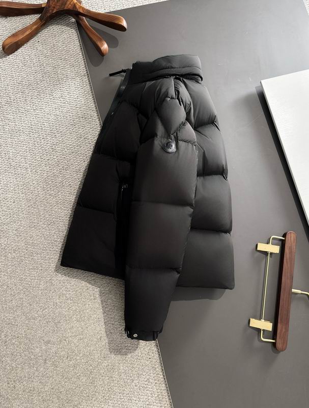 Black puffer jacket on a gray surface with a wooden stand in the background