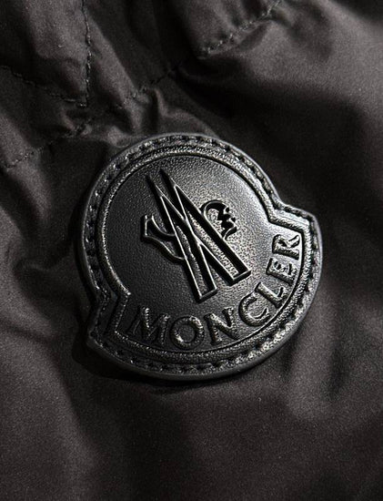 Close-up of a Moncler logo on a black fabric background