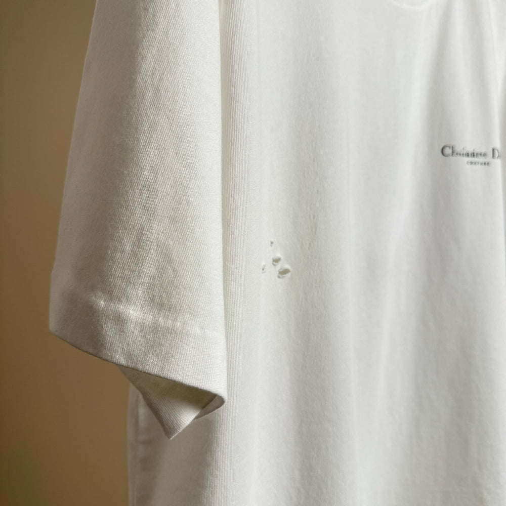 Christian Dior Couture Close-up of a beige shirt with a brand logo on a beige background