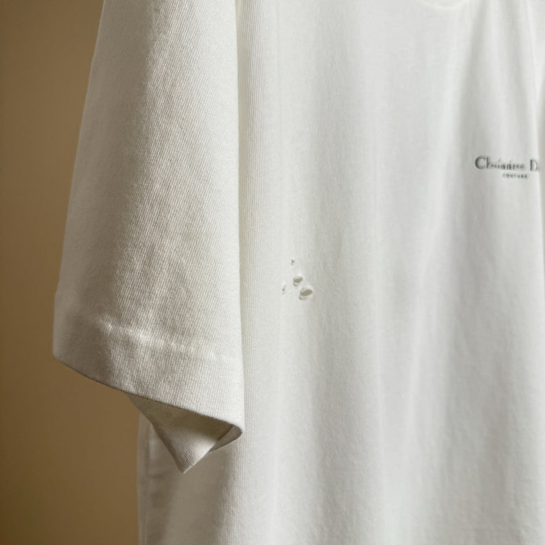 Christian Dior Couture Close-up of a beige shirt with a brand logo on a beige background
