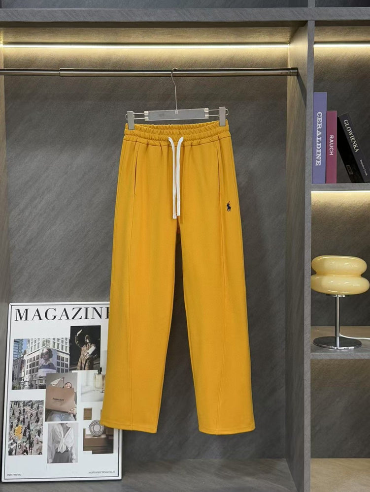 Ralph Lauren Women's Pony Straight Leg Pants. Yellow pants hanging on a rack with a magazine and books in the background.