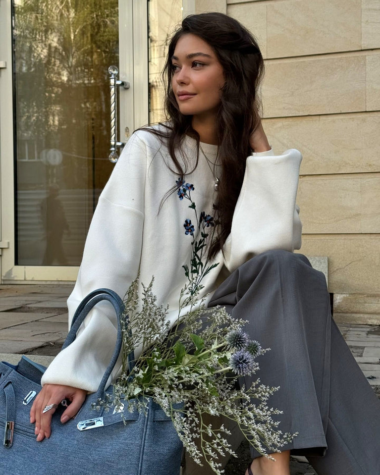 Woman wearing Women's Autumn Winter Thin Overhead Casual Sweater, sitting with flowers and a blue handbag.
