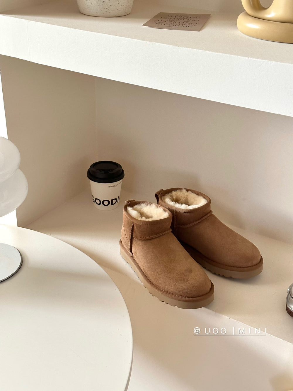Brown UGG boots on a white shelf with a coffee cup in the background