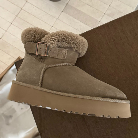 Beige suede boot with fur trim and buckle on a wooden floor. UGG Furry Belted Women's Snow Boot with Thick Platform Sole at Volonka