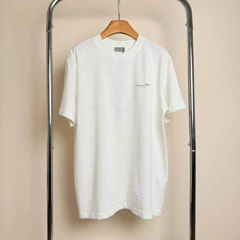 Christian Dior Couture White t-shirt with a small logo on a wooden hanger against a beige background