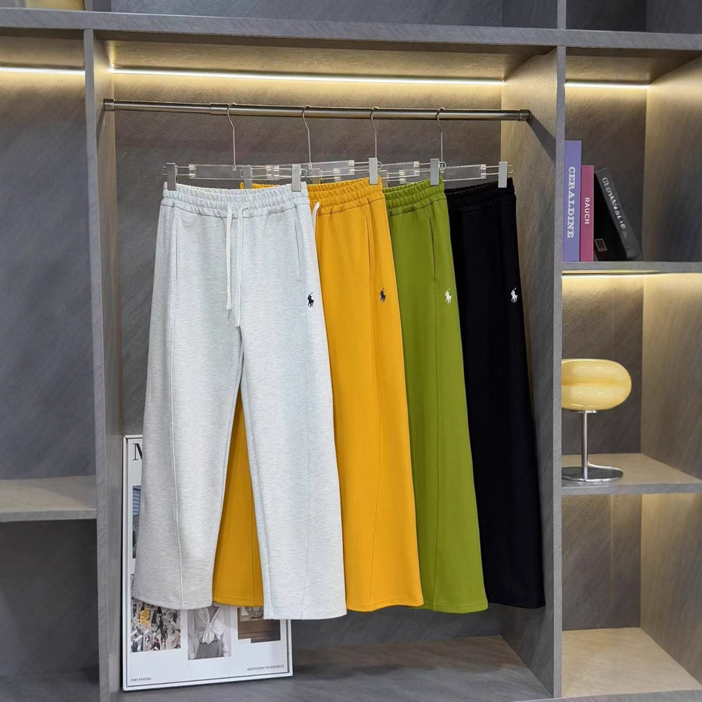 Four pairs of pants in gray, yellow, green, and black hanging on a rack. Ralph Lauren Women's Pony Straight Leg Pants 