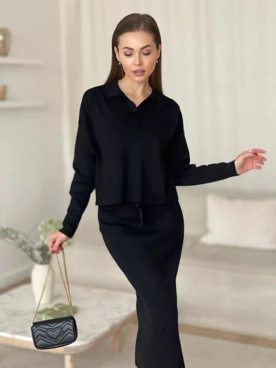 Woman in a black outfit holding a matching handbag in an elegant room.